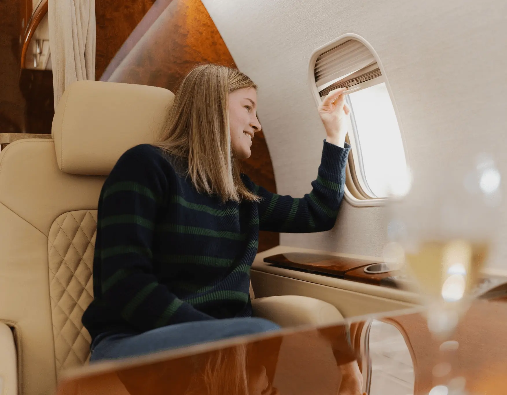 Passagère assise dans un avion privé regardant par le hublot, dans un intérieur confortable et lumineux.